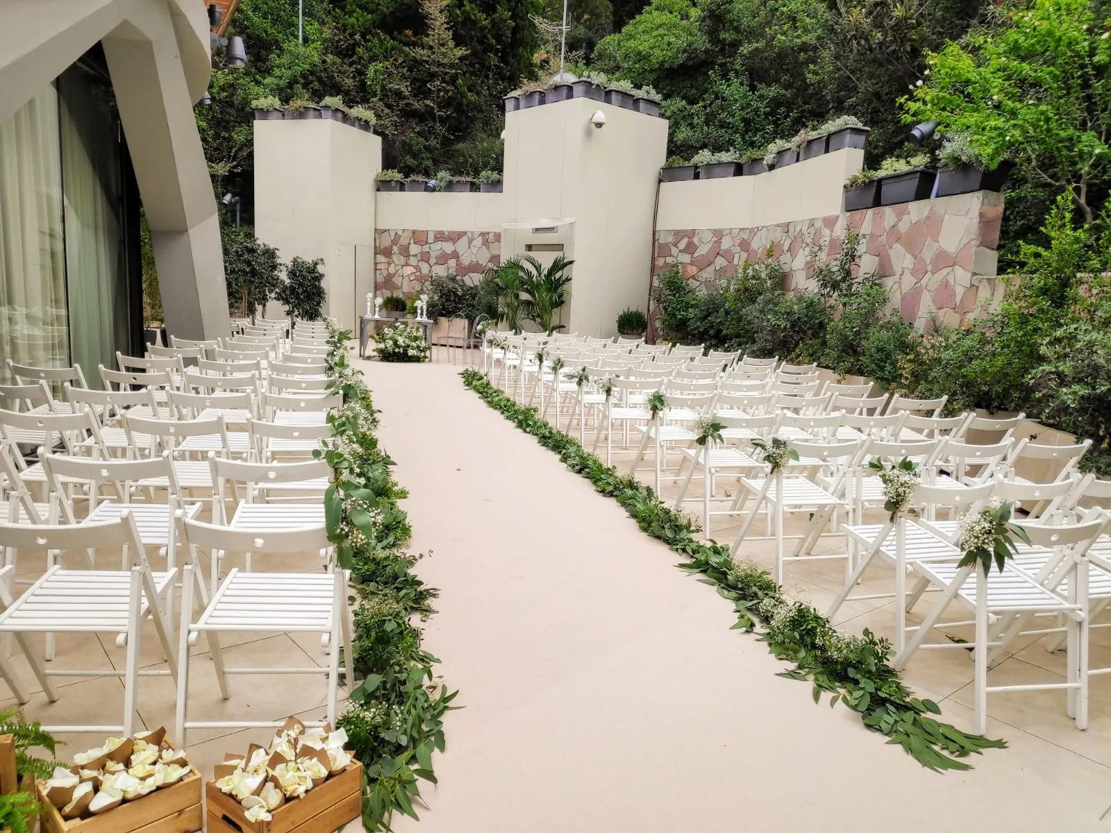 Ceremonia al aire libre con sillas blancas y pasillo de pétalos en Esferic Montjuïc