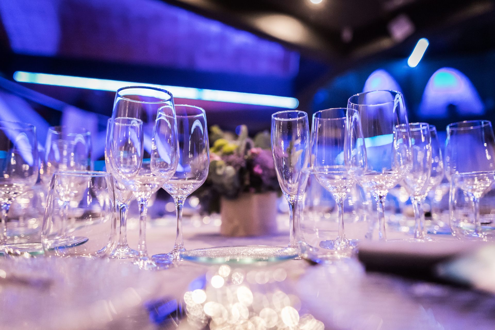 Mesa de evento con copas de cristal e iluminación azul