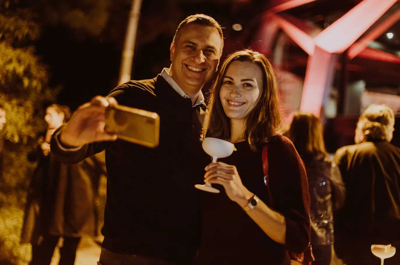 Pareja en evento nocturno con copa en mano